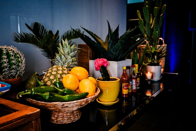 An assortment of decorations adorning the taco bar: cacti, sauces, and fruit.