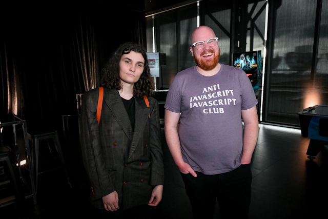 Two Astro core members, Erika and Nate, post together. Nate wears an, "Anti Javascript Javascript Club," t-shirt.