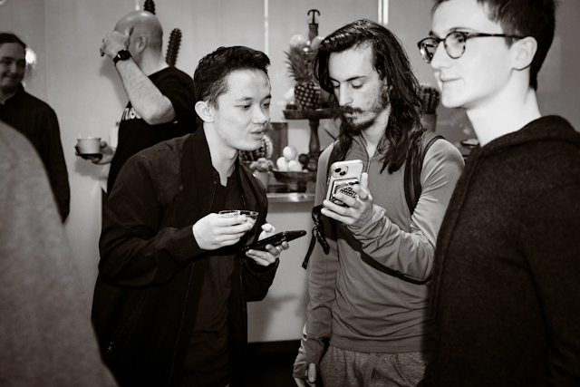 Black and white photo of a guest reading the phone screen of another guest.