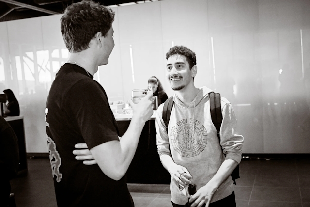 Black and white photos of two male guests chatting with one another.