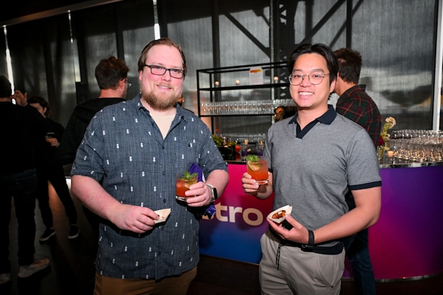 Two male guests posing with their appetizers and drinks.