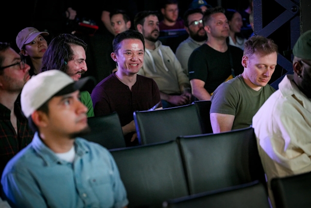 A smiling audience member amidst the crowd of people listening to the keynote presentation.