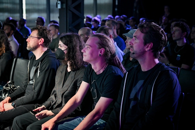 A shot of the front row listening to Ben Holmes speak on stage.