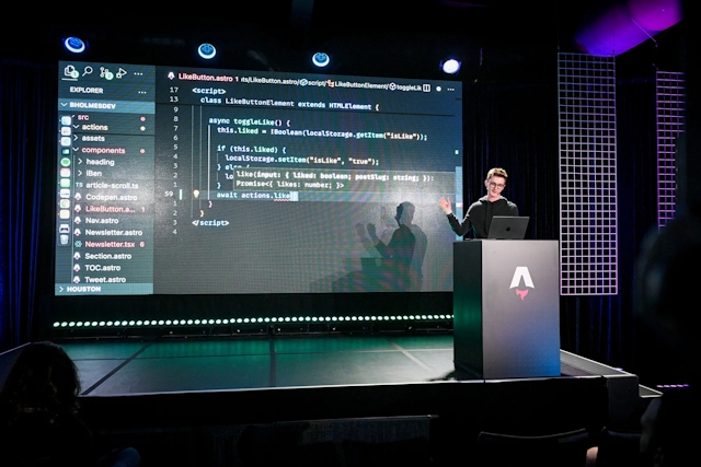 Ben Holmes speaking from an Astro-branded podium. His hand points to a code example of a like button component