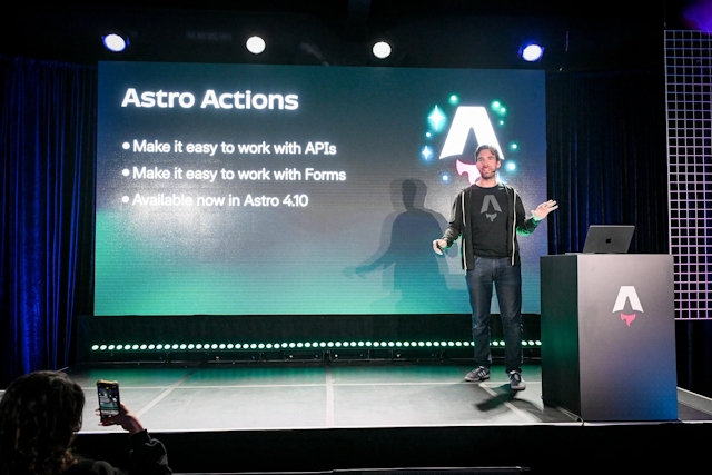 Fred K. Schott speaking on stage next to an Astro-branded podium. He is summarizing Astro Actions, which Ben Holmes just presented on.