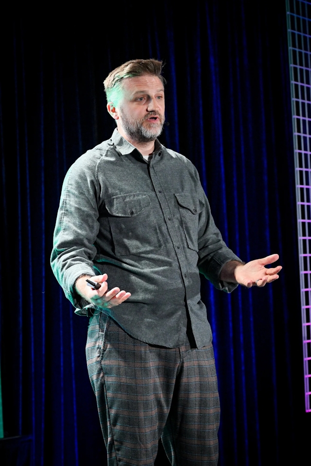 Portrait shot of Matthew Phillips speaking on stage.