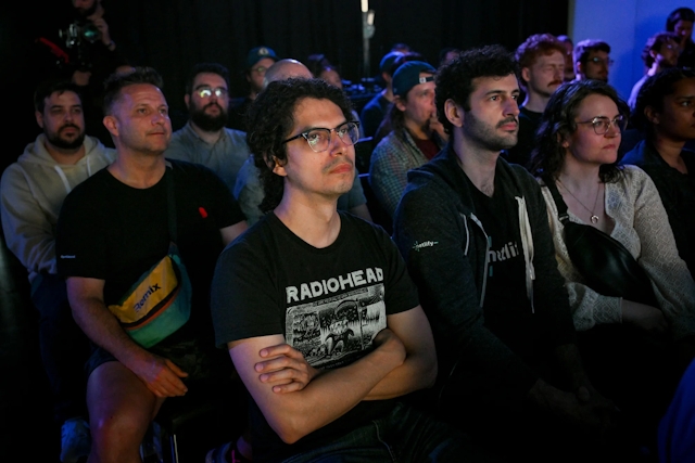 Audience members listening to Sarah Rainsberger speaking on stage.