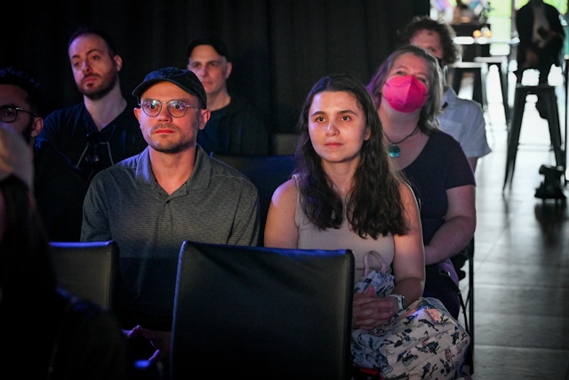 Audience members listening to Sarah Rainsberger speaking on stage.