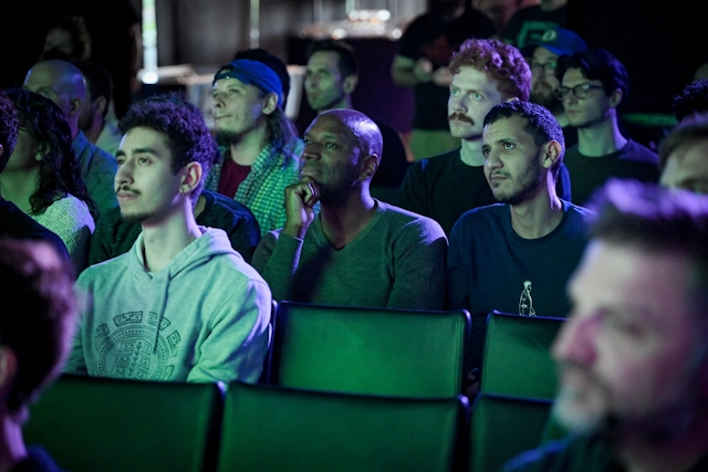 Audience members gazing intently at Fred K. Schott speaking on stage.