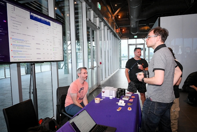 A guest speaks to Sentry at their sponsor booth.