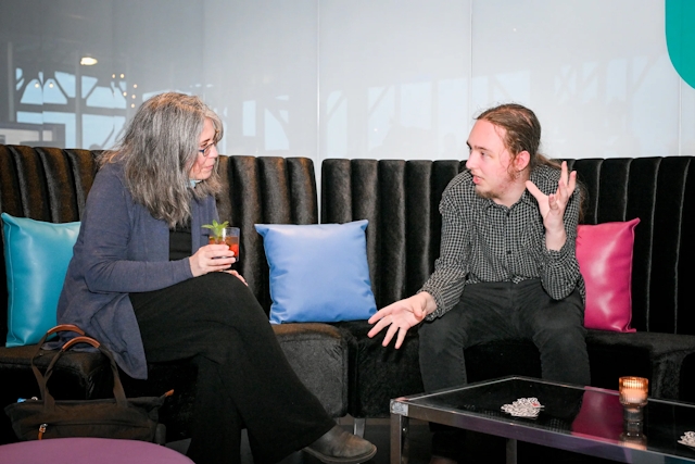 Reuben, of Astro, sitting it the Houston lounge chatting with a guest as she holds her drink.