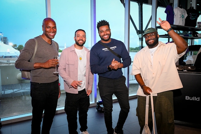 Guests pose for a group photo in front of floor-to-ceiling windows.