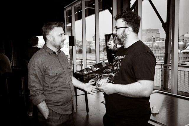 Black and white photo of Matthew Phillips chatting with a guest.