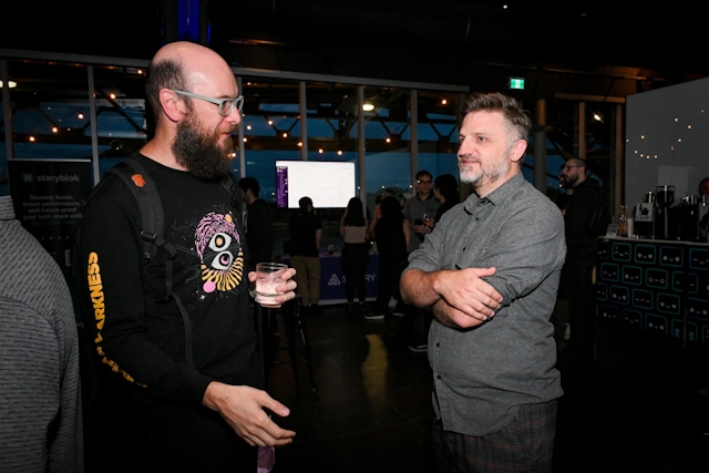 Matthew Phillips chatting with a guest. It is now so dark that the rest of the guests are hard to see and you do not see much outside the window.